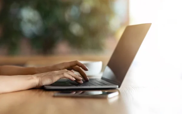 Mulher irreconhecível digitando no laptop no café — Fotografia de Stock