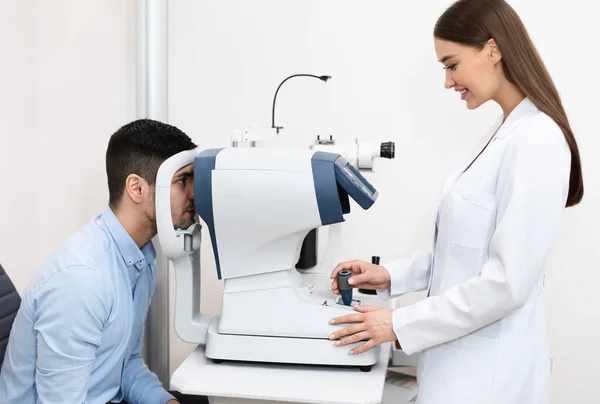 Optometrista che controlla la visione dei pazienti presso la moderna clinica — Foto Stock