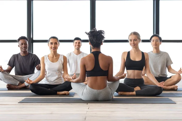 Clase de yoga. Hombres y mujeres multiétnicos que tienen clase grupal con instructora femenina — Foto de Stock