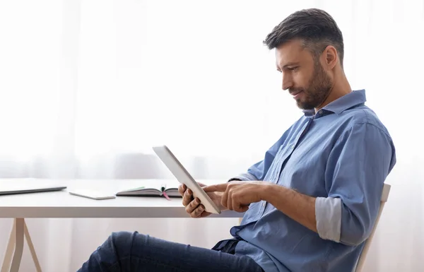 Hombre freelancer guapo usando tableta digital mientras tiene descanso en el trabajo — Foto de Stock