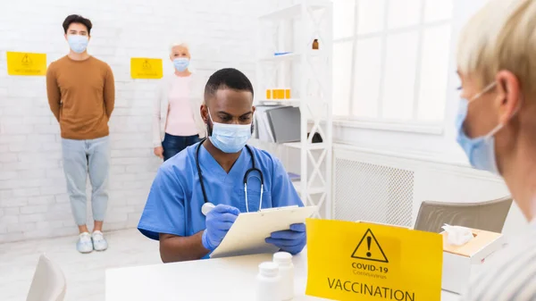 Lékař pracující s pacienty během očkovací kampaně proti koronaviru v nemocnici — Stock fotografie