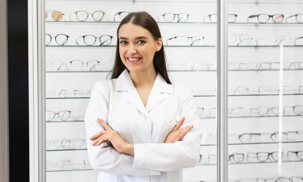 Mujer feliz optometrista de pie en la tienda de óptica —  Fotos de Stock