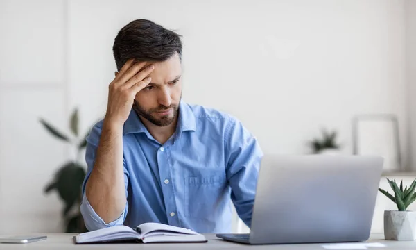 Empreendedor masculino concentrado olhando para a tela do portátil enquanto trabalhava no escritório moderno — Fotografia de Stock