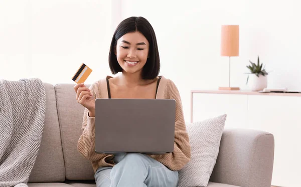 Young asian woman making purchases sitting on the couch — Stock Photo, Image