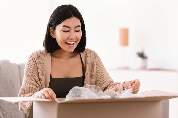 Glücklich asiatisch frau auspacken paket nach online shopping — Stockfoto