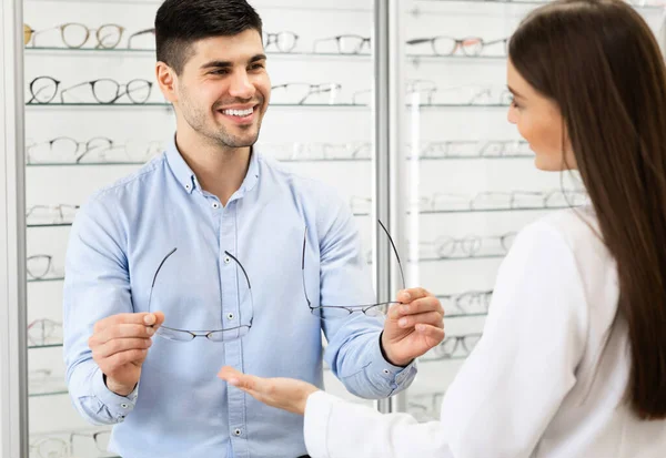 Optometrista ayudando al hombre a elegir nuevas gafas de corrección —  Fotos de Stock