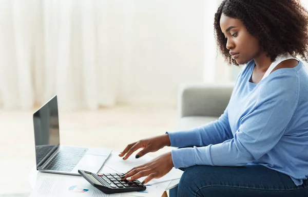 Mulher negra usando calculadora e laptop pc em casa — Fotografia de Stock