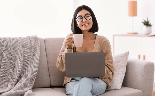 Young asian woman using laptop and drinking coffee — Stock Photo, Image