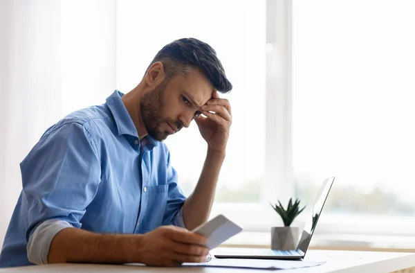 Besorgter junger Geschäftsmann schaut im Büro auf Smartphone und wartet auf Nachricht — Stockfoto