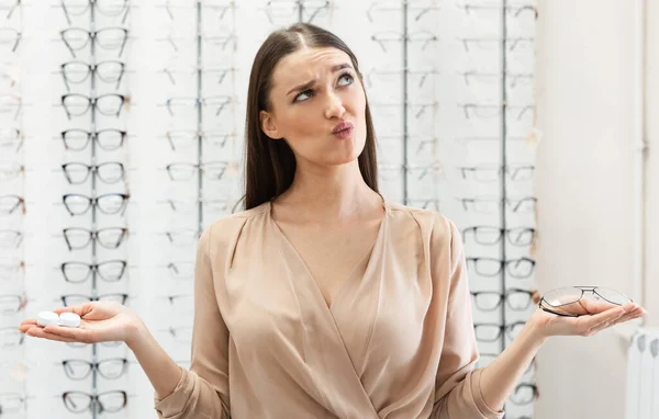 Signora pensierosa che sceglie tra occhiali e contatti — Foto Stock