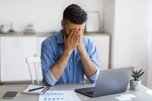 Stanchezza dal lavoro. Imprenditore maschio stressato che copre il viso con le mani sul posto di lavoro — Foto Stock