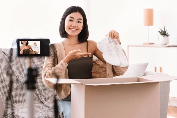 Happy asian woman recording video blog unpacking parcel