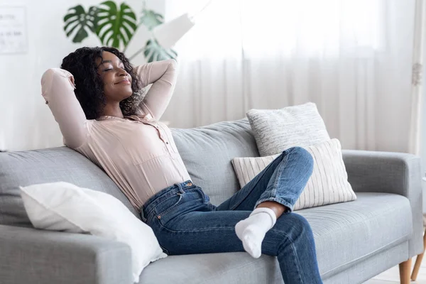 Week-end à la maison. Femme afro-américaine détendue penchée sur le canapé — Photo