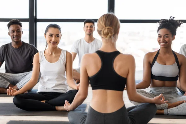 Grupp av mångkulturella män och kvinnor som utövar yoga med instruktör i studio — Stockfoto