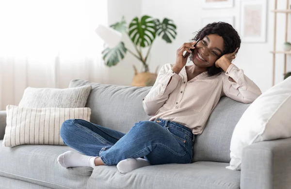 Κινητή επικοινωνία. Χαρούμενη Αφρικανή που μιλάει στο κινητό με φίλους στο σπίτι. — Φωτογραφία Αρχείου