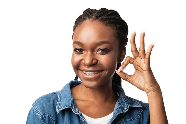Afrikansk amerikansk kvinna med hängslen Gesturing Okay över vit bakgrund — Stockfoto