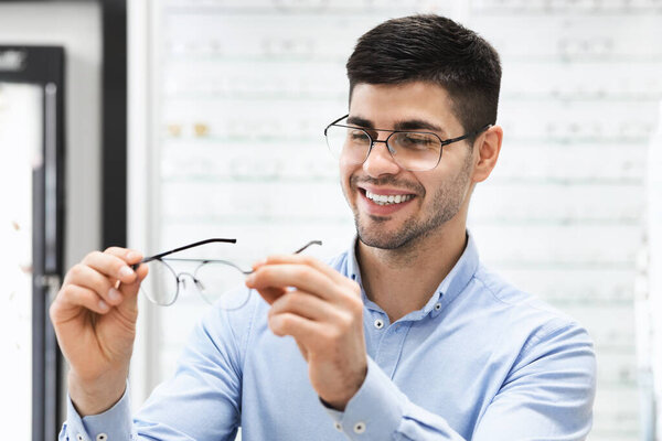 Portrait of handsome young guy choosing spectacles