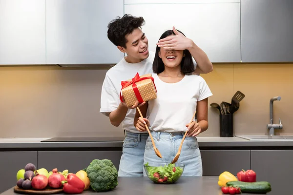 Asian Husband Preparing Surprise Gift For Wife Standing In Kitchen — Stock Photo, Image