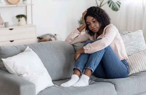 Conceito de depressão. Solitário chateado afro-americano mulher sentada no sofá em casa — Fotografia de Stock