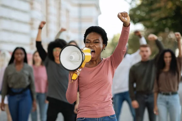 Черная женщина с мегафонной группой демонстрантов — стоковое фото