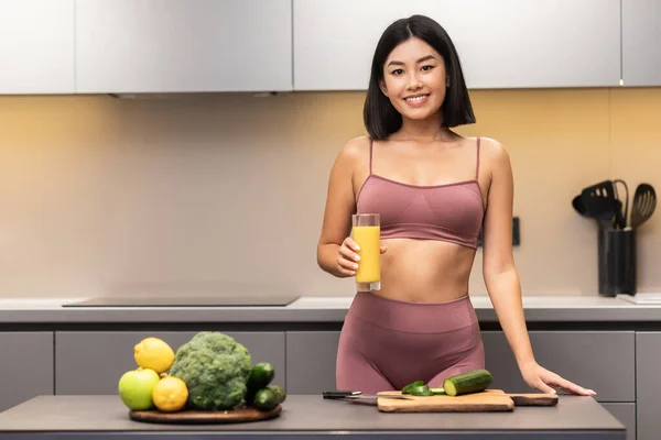 Glada smala japanska kvinna dricka juice matlagning middag i köket — Stockfoto