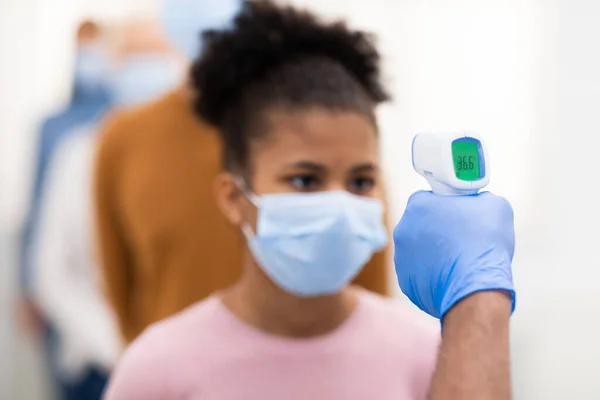 Médico trabajador haciendo pruebas de temperatura para las personas en la cola en interiores — Foto de Stock