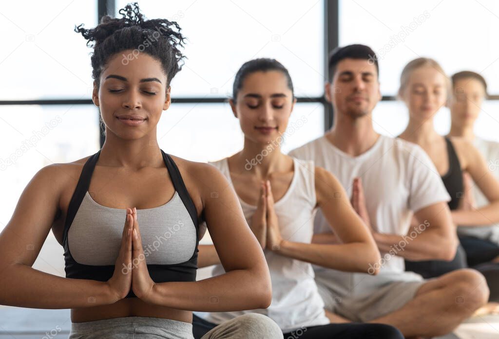 Yoga Class. Young Sporty Multicultural People Sitting In A Row, Meditating Together