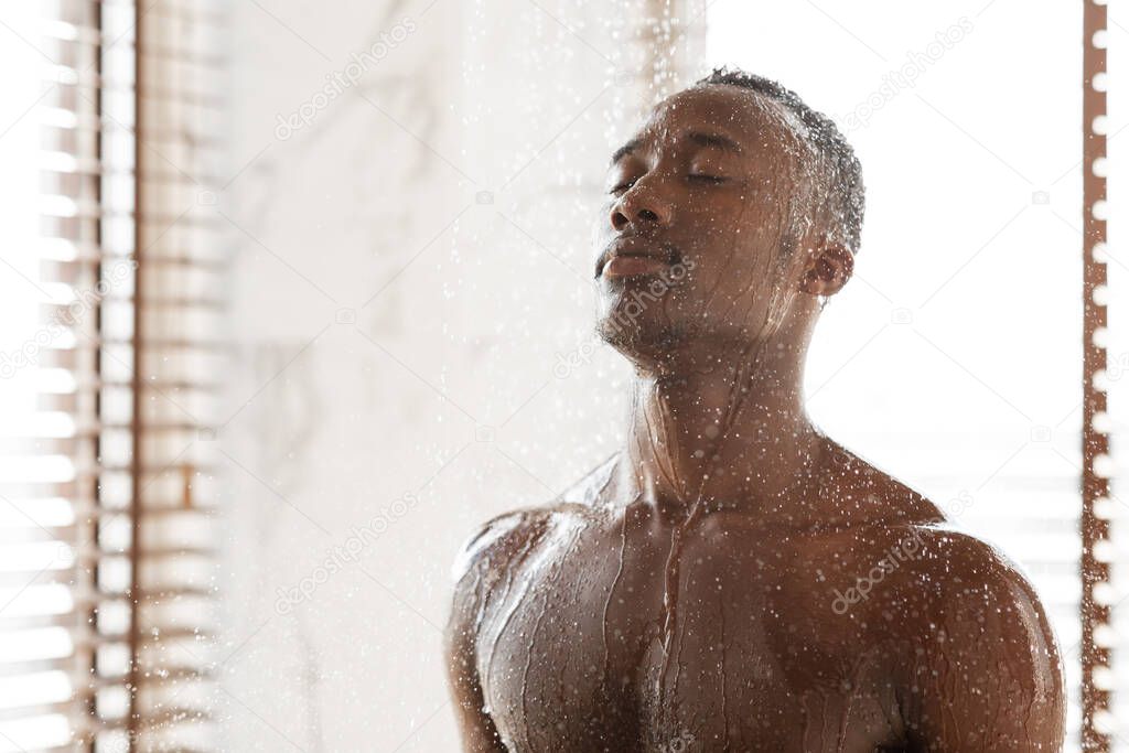 Black Man Taking Relaxing Shower Standing With Eyes Closed Indoors