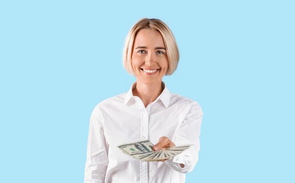 Retrato de sorridente senhora de negócios segurando muito dinheiro sobre fundo estúdio azul, panorama — Fotografia de Stock