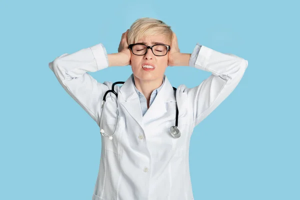 Medicinska problem, överansträngning eller kranskärlssjukdom. Tråkig kvinna läkare i vit rock med stetoskop — Stockfoto
