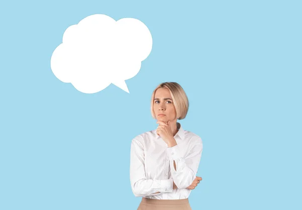 Puzzled zakenvrouw met spraakbel op blauwe studio achtergrond, mockup voor ontwerp — Stockfoto