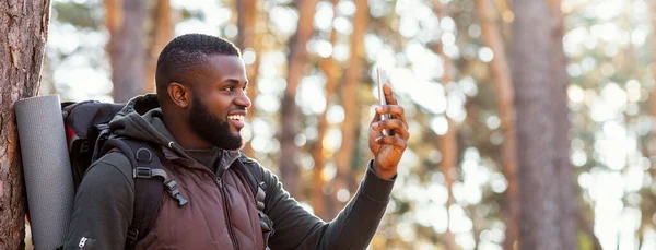 Afrikanischer Backpacker mit Smartphone im Wald — Stockfoto