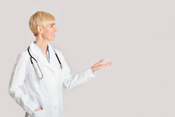 Gezondheidszorg, medische professionals en bezoek aan de dokter. Vriendelijke vrouwelijke punten met de hand op lege ruimte — Stockfoto