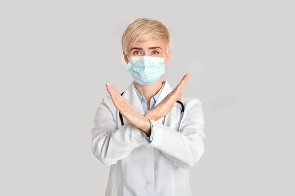 疫病を止めなさい。中年の女性医師は、病気やコロナウイルスと戦うために彼女の手でジェスチャーを行います — ストック写真
