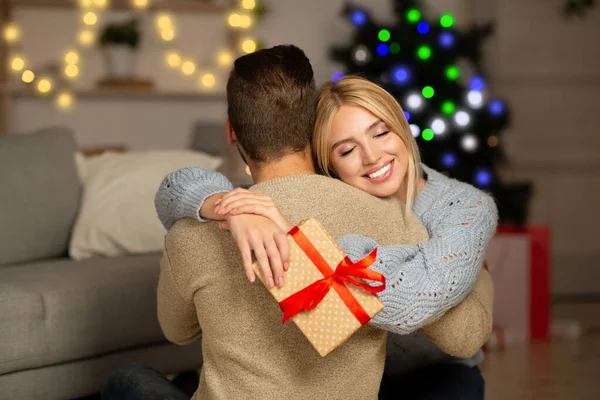 크리스마스 선물을 들고 남편을 껴안고 기뻐하는 아내 — 스톡 사진