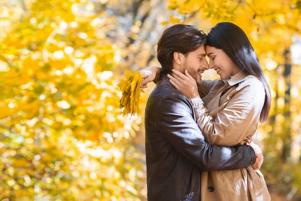 Liefdevolle man en vrouw knuffelen tijdens het wandelen door gouden bos — Stockfoto