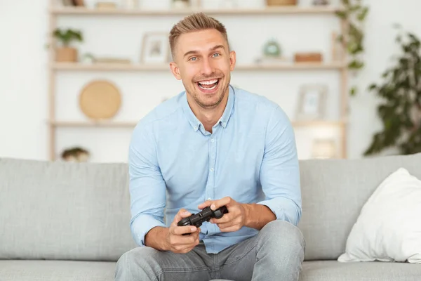 Izgatott érzelmi srác ül a kanapén videojáték — Stock Fotó