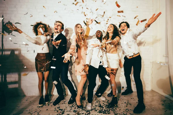 Felice Millennials celebrando divertirsi in piedi sotto caduta Confetti Indoor — Foto Stock