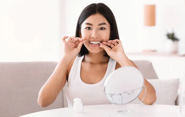 Jeune dame asiatique à l'aide de fil dentaire regarder dans le miroir — Photo
