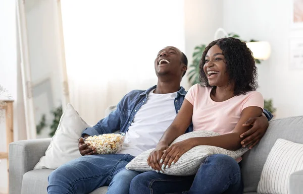 Riendo negro hombre y mujer viendo película juntos en casa —  Fotos de Stock