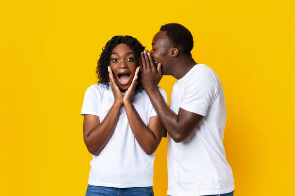 Hombre negro compartiendo secreto con su novia asombrada — Foto de Stock