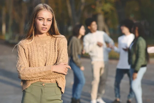 Frustrerad blond flicka stående över grupp tonåringar — Stockfoto