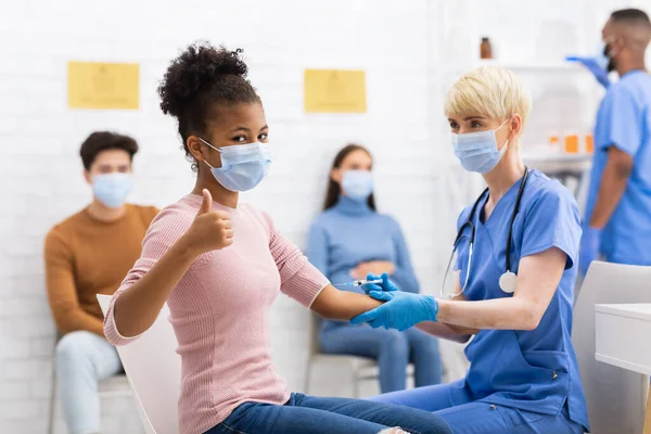 Black Girl Gesturing Thumbs-Up recevant l'injection de vaccin contre le coronavirus à l'hôpital — Photo