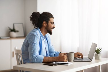 Uzaktan kumanda. Erkek Serbest Çalışan Laptop kullanıyor ve İçişleri Bakanlığı 'nda kahve içiyor.
