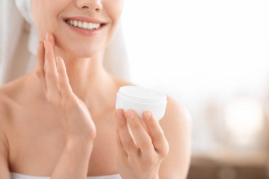 Tanımlanamayan gülümseyen kadın yüz kremi sürüyor, kopyalama alanı