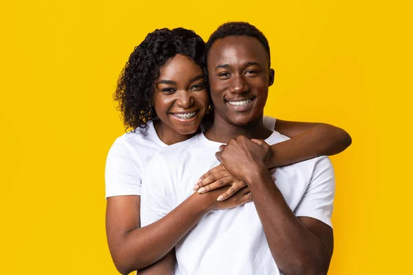 Feliz negro pareja en amor abrazando en amarillo — Foto de Stock