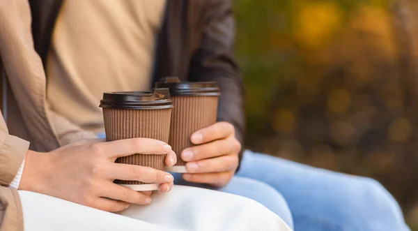 Männliche und weibliche Hände halten heiße Drinks, während sie draußen sitzen — Stockfoto