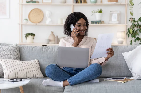 Femme travaillant avec des documents et un ordinateur portable et parlant sur un téléphone portable à la maison — Photo