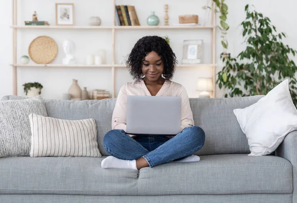 Trabajo independiente. Sonriente dama afroamericana trabajando en computadora portátil en casa —  Fotos de Stock