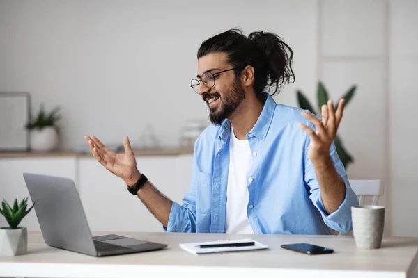 Захоплений індійський чоловік емоційно відзначає успіх бізнесу з ноутбуком в офісі — стокове фото